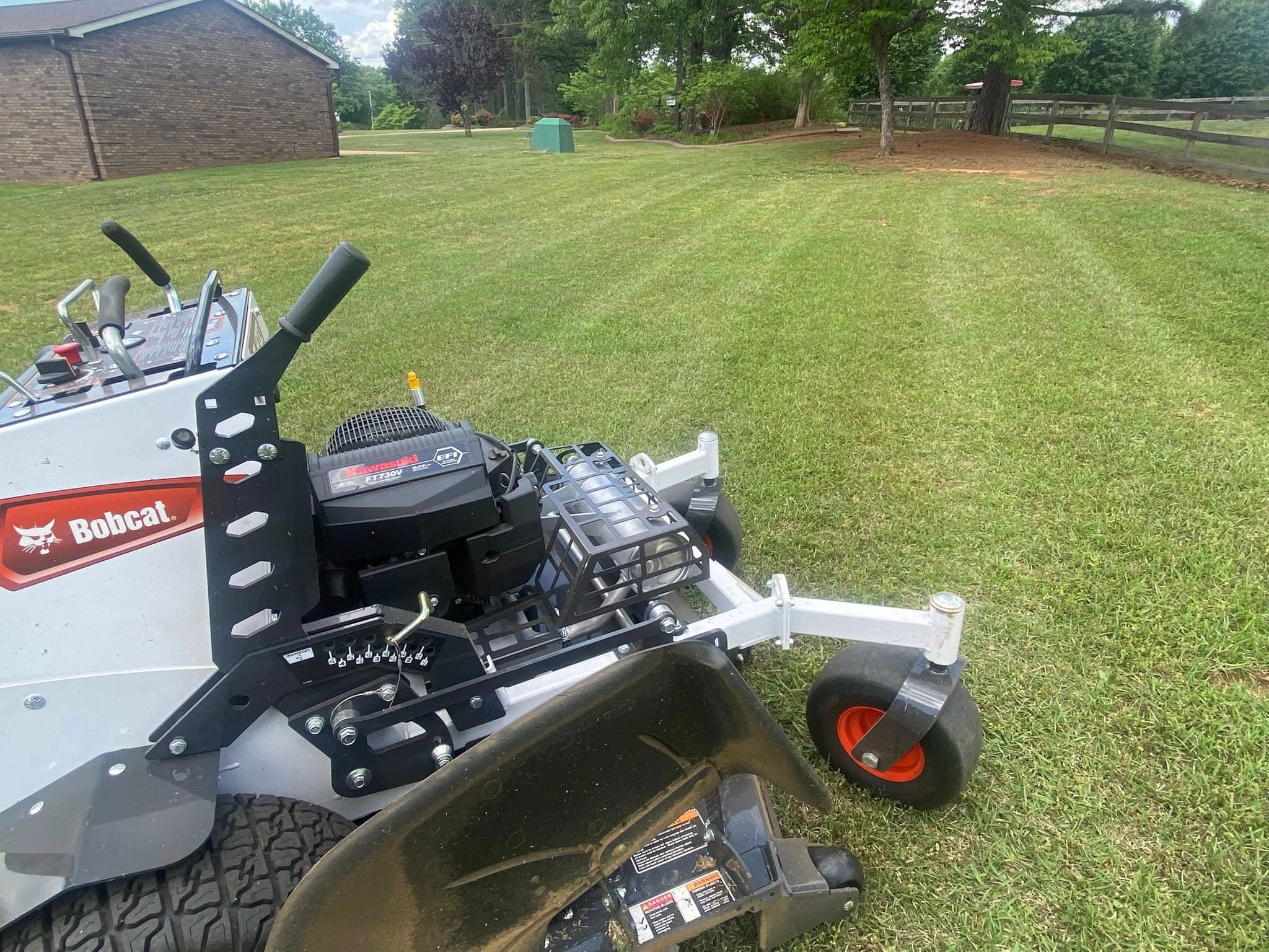 Bobcat mower creating clean stripes on a lawn maintained by Mooe's Landscaping